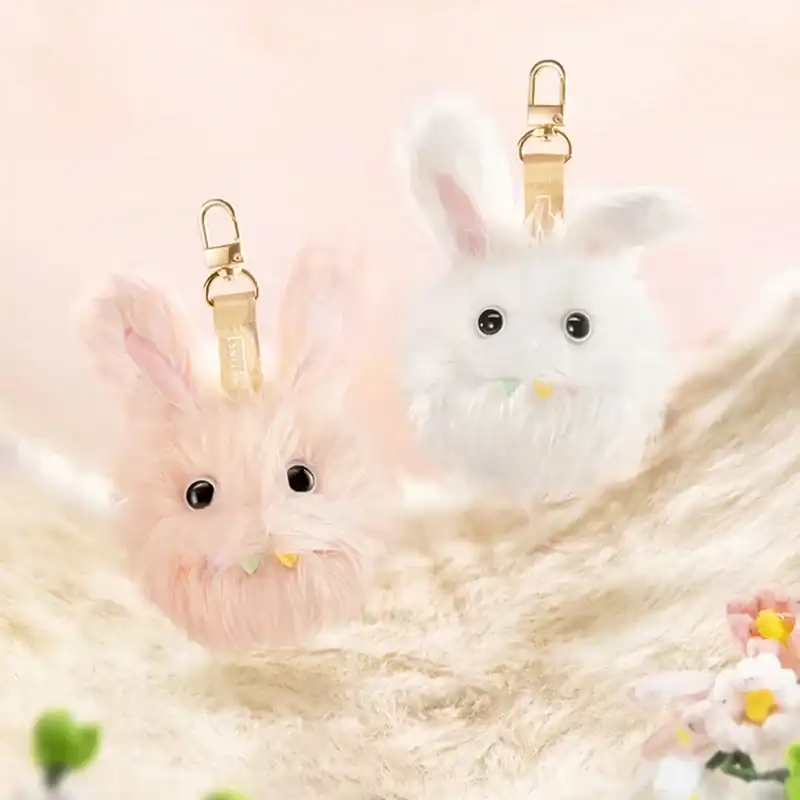 Pink bunny plush keychain with fluffy fur and black eyes.
